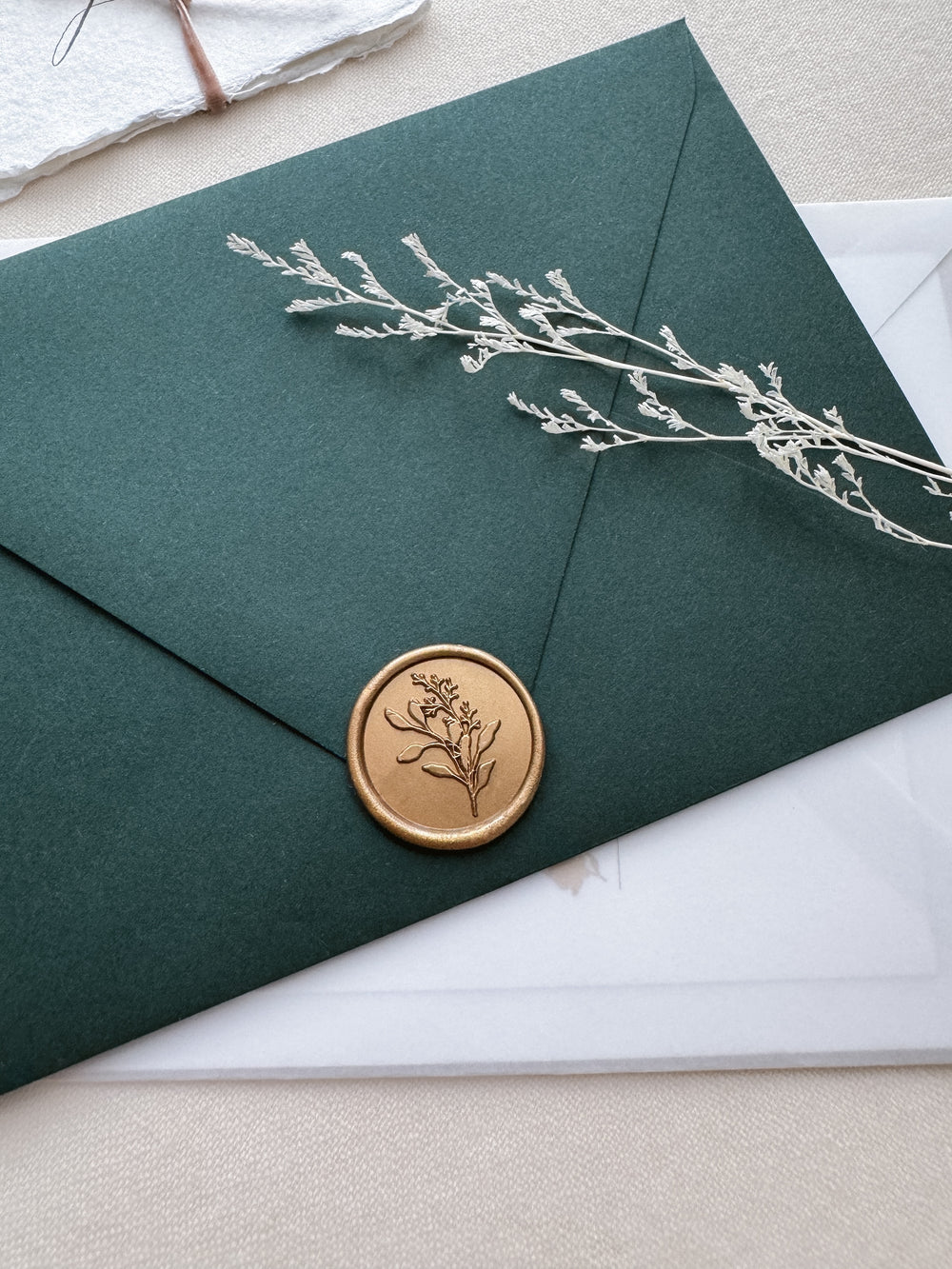 Gold eucalyptus botanical wax seal on a dark green envelope