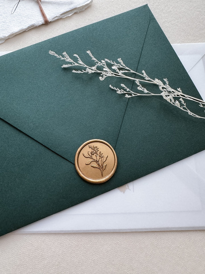 Gold eucalyptus botanical wax seal on a dark green envelope