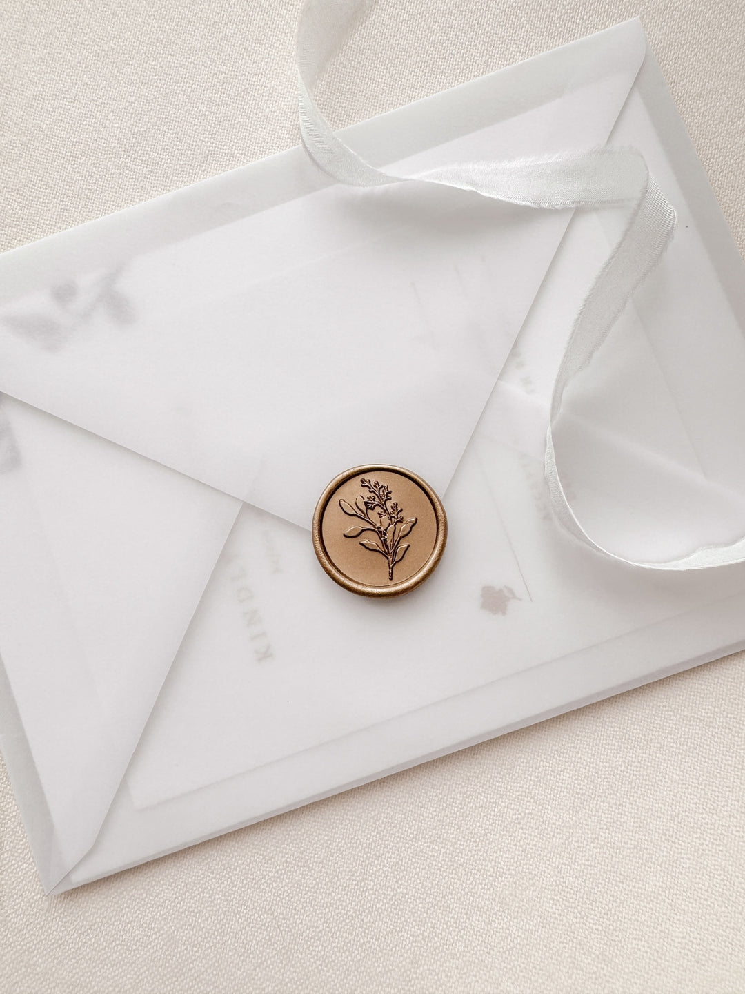 Gold eucalyptus bouquet wax seal on a translucent vellum wedding invitation envelope