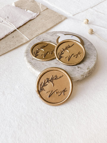 Floral branch monogram custom wax seals in gold styled with a small gray stone dish, handmade paper and a dried floral branch