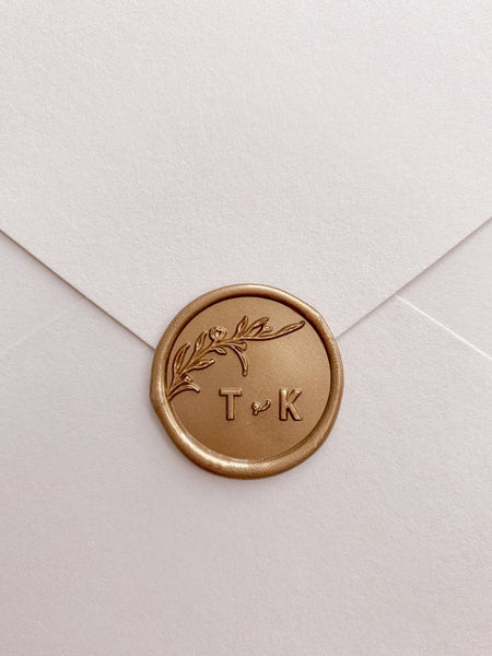 Floral branch monogram gold custom wax seal with typeface letters on beige paper envelope