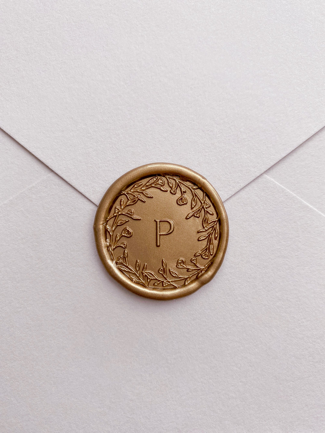 Floral crown single initial gold custom wax seal on beige paper envelope