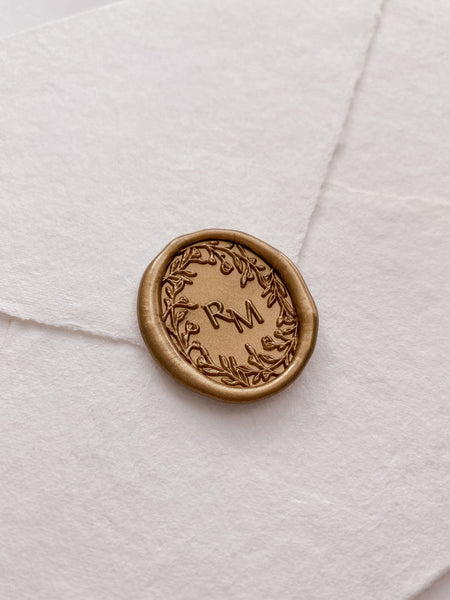 Oval floral crown monogram wax seal in gold on handmade paper envelope_side angle