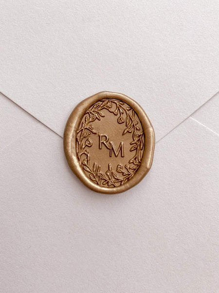 Oval floral crown monogram wax seal in gold on paper envelope 