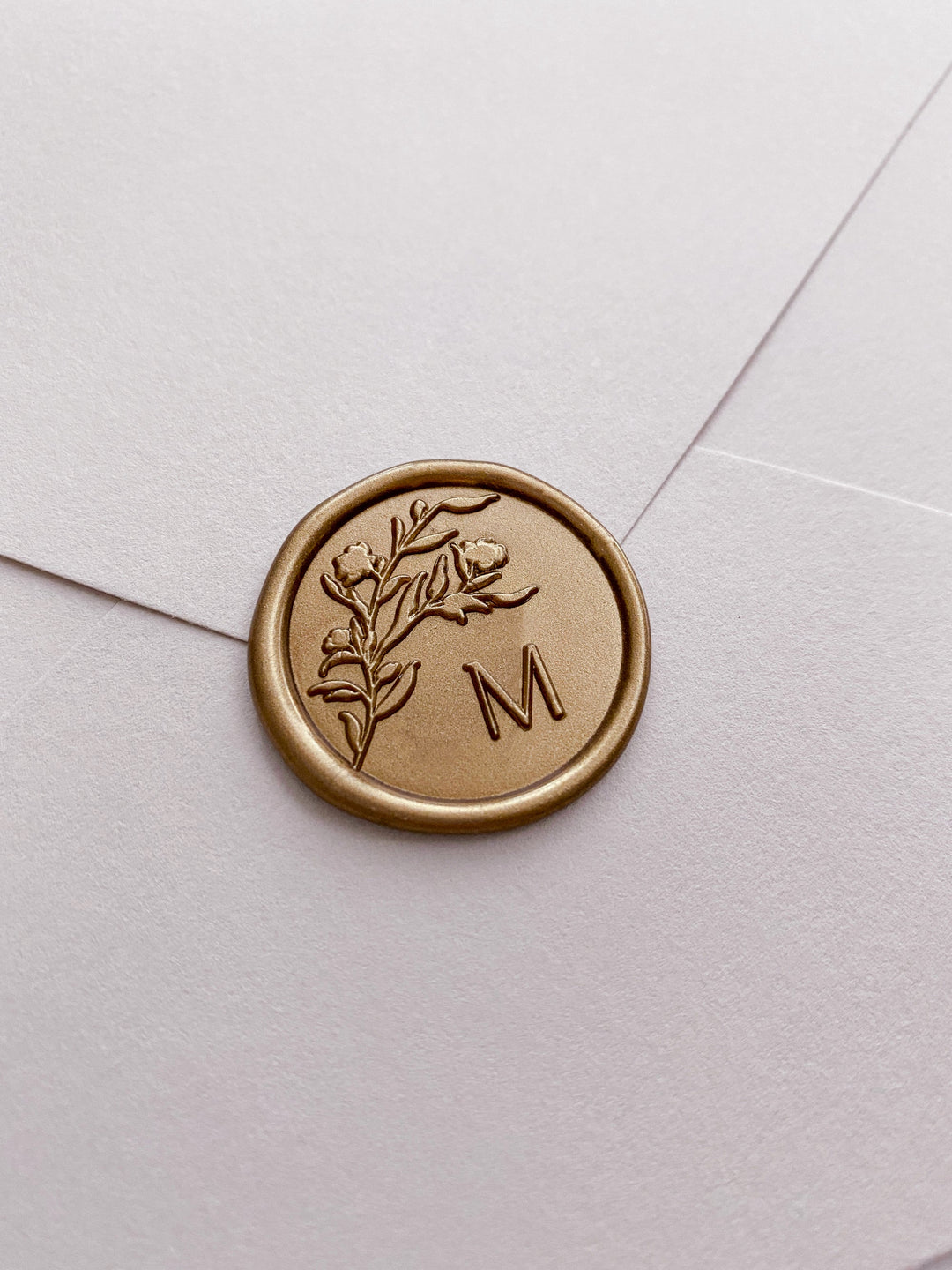 Floral silhouette single initial gold custom wax seal on beige paper envelope