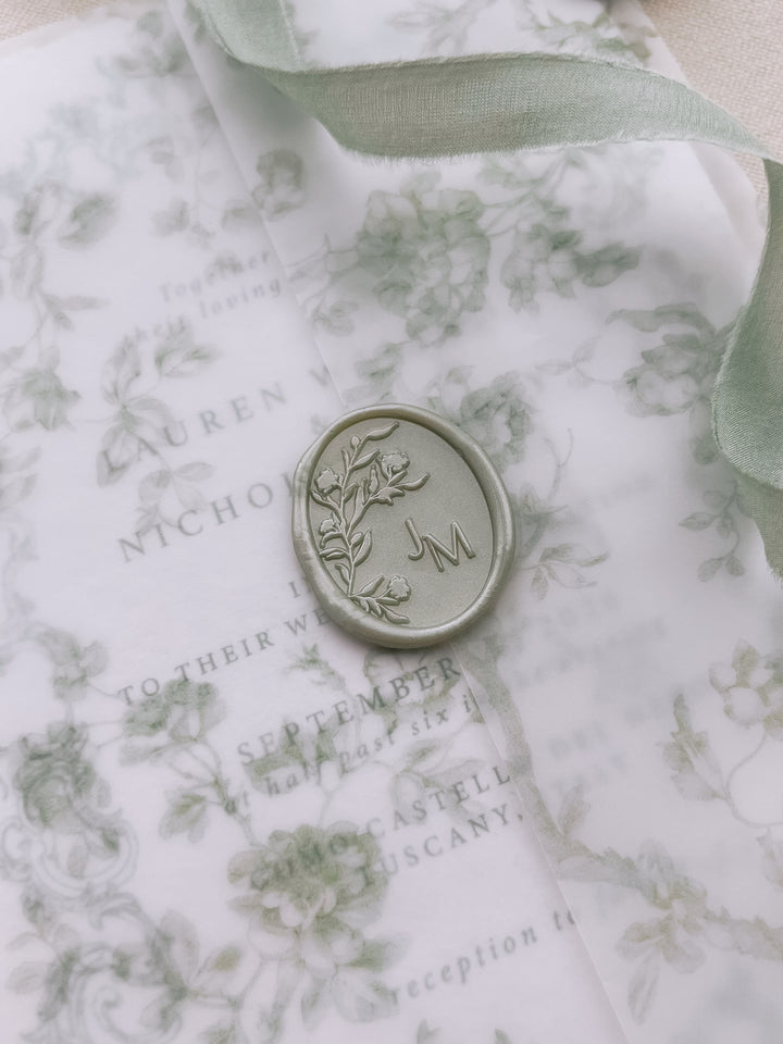 Light metallic green oval floral monogram wax seal with personalized initials on a green floral print vellum jacket