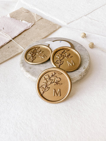 Floral crown monogram single initial custom wax seals in gold styled with a small gray stone dish, handmade paper and a dried floral branch