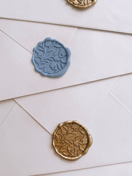 Dusty blue and gold floral silhouette wax seals on beige envelopes