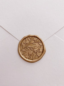Floral silhouette wax seal in gold_front angle on paper envelope