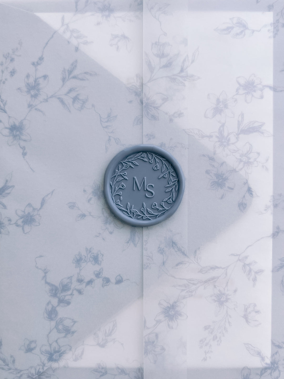 Dusty blue floral wreath custom wax seal with personalised initials on a blue floral print vellum jacket
