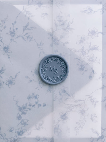 Dusty blue floral wreath custom wax seal with personalised initials on a blue floral print vellum jacket