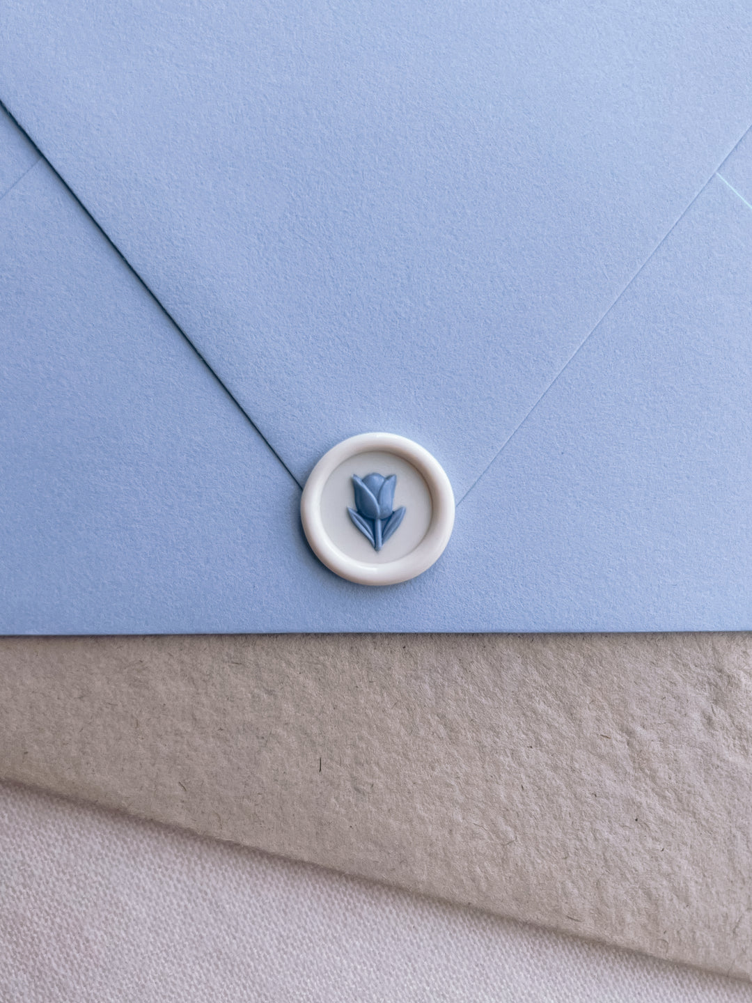 white and blue 3D flower emoji mini wax seal on a blue envelope