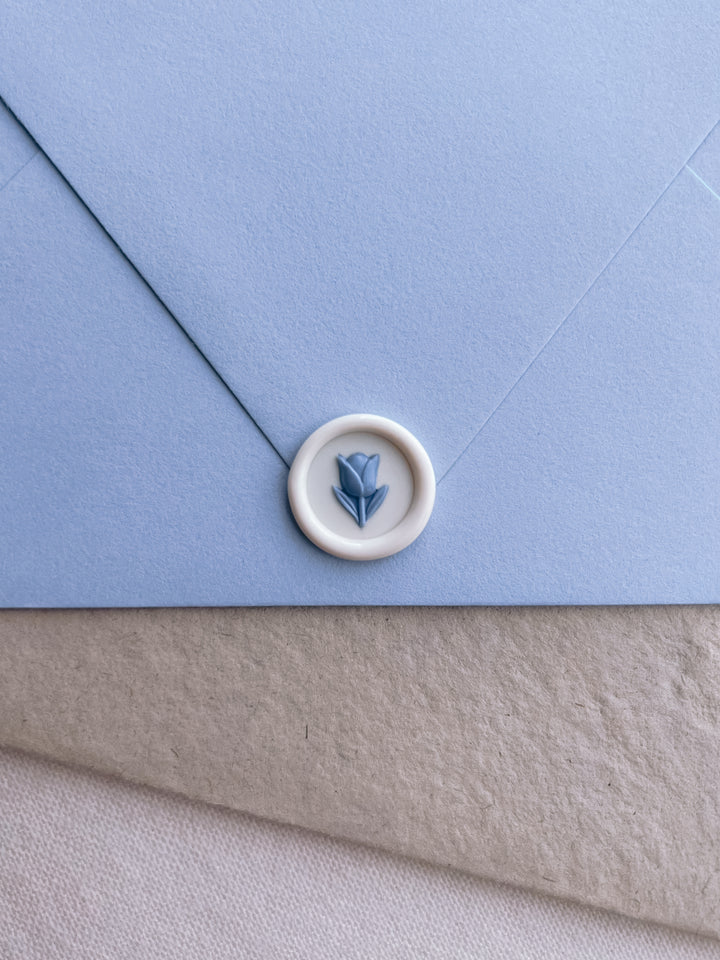 white and blue 3D flower emoji mini wax seal on a blue envelope