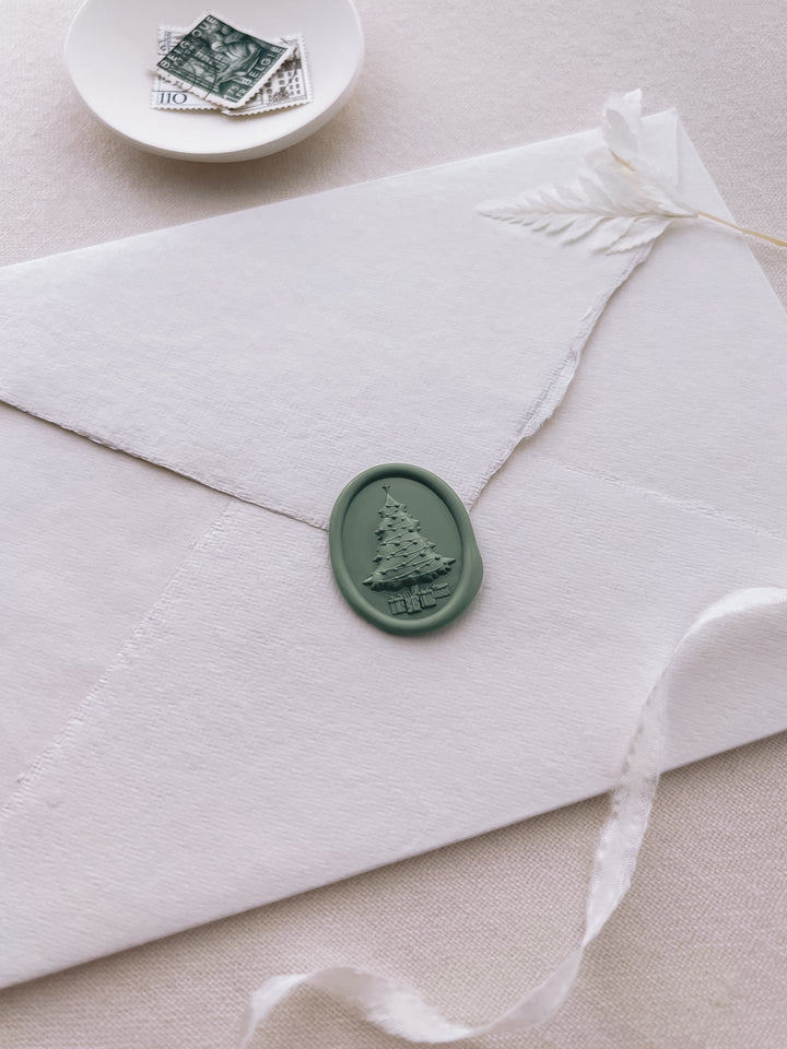 Sage green 3D Christmas tree oval wax seal on a white deckled edge handmade paper envelope 