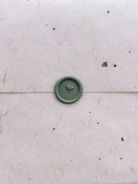 3D flower design green wax seal on a beige envelope