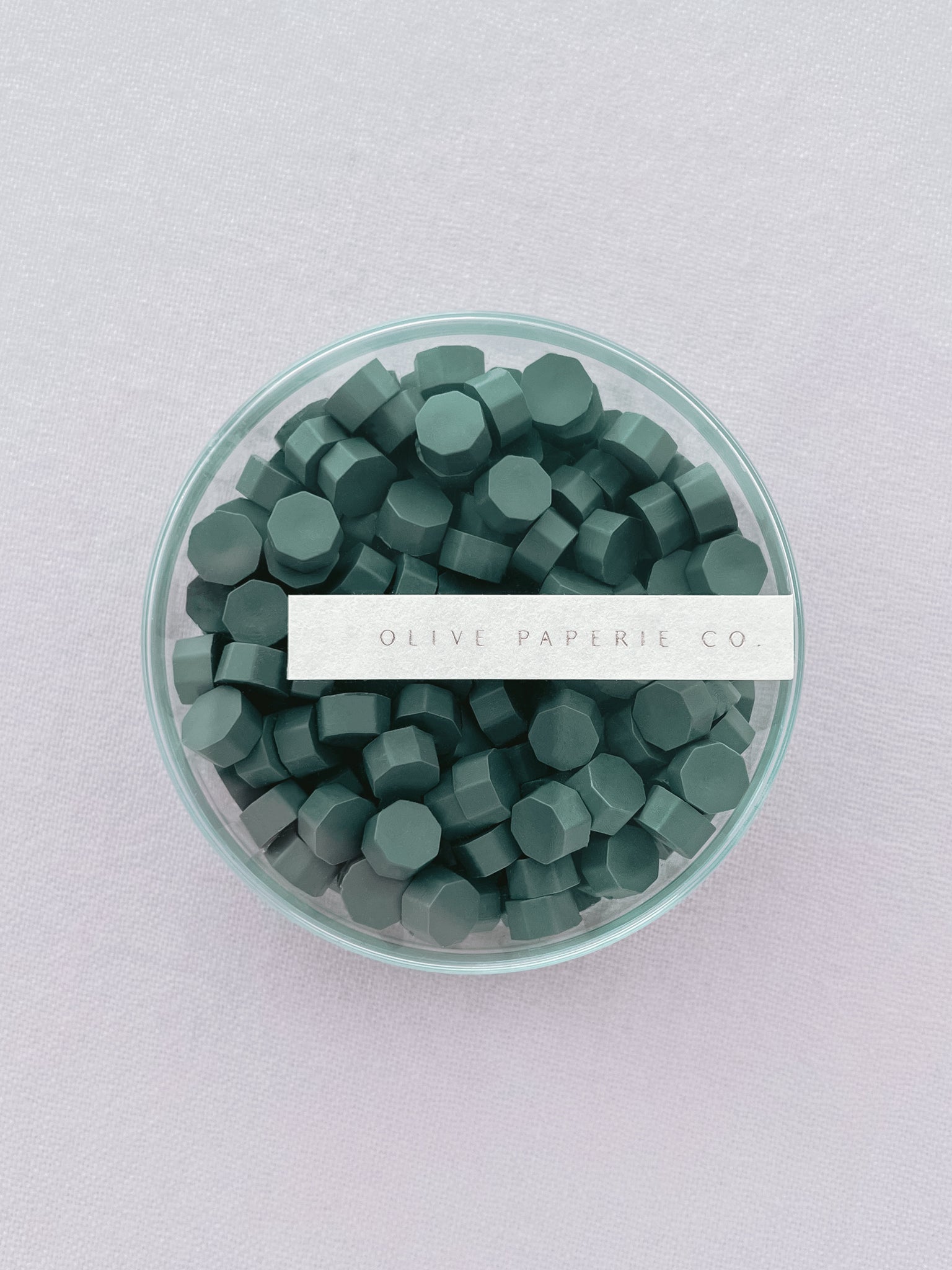 Non-metallic pine green sealing wax beads in a clear container box