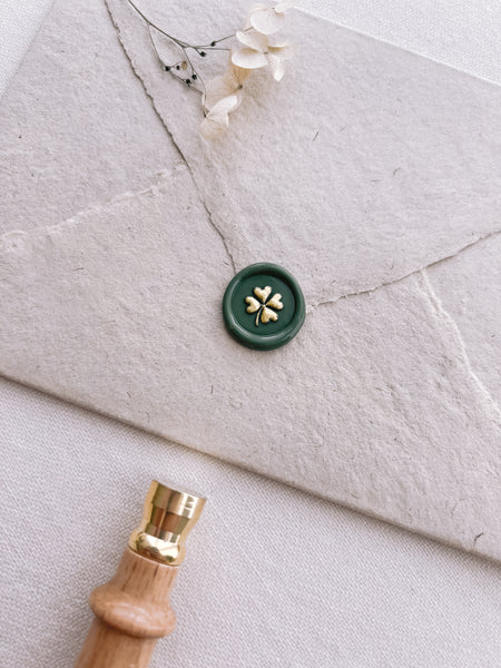 dark green wax seal with four leaf clover design painted in gold