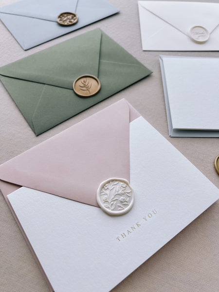 gold foil thank you card with light pink envelope and floral white wax seal 