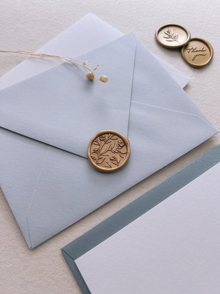 light blue envelope with gold flower wax seal 