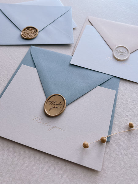 beige thank you card with dusty blue envelope and gold thank you wax seal