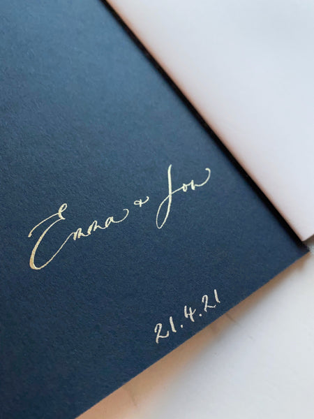 Personalized names and wedding date in calligraphy on the inner cover of a navy blue vow book