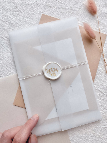 a gold leaf white wax seal on translucent envelope with white twine