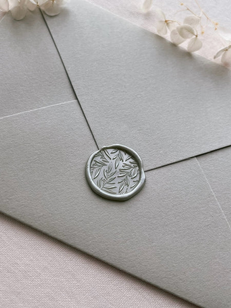 metallic sage green wax seal of a 3D leaf pattern on a light sage envelope