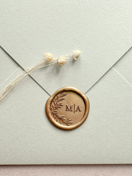 botanical leaf design monogram gold wax seal on a sage green envelope