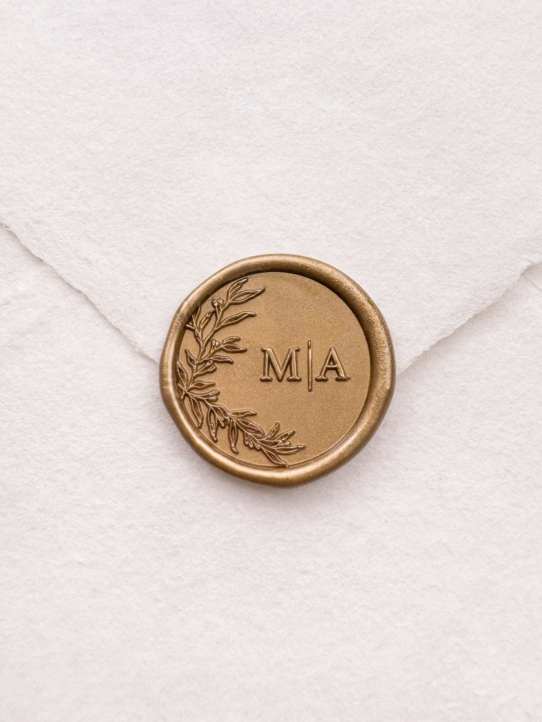 Personalized initials gold wax seal featuring a custom botanical monogram on a white deckled edge handmade paper envelope