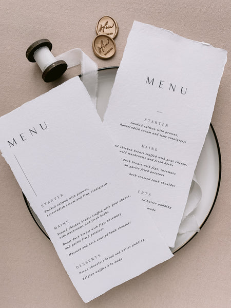 Handmade paper menus with natural deckled edges on table setting in design 4 and 5 with white silk ribbon and Olive Paperie Co. wax seals in gold as decoration