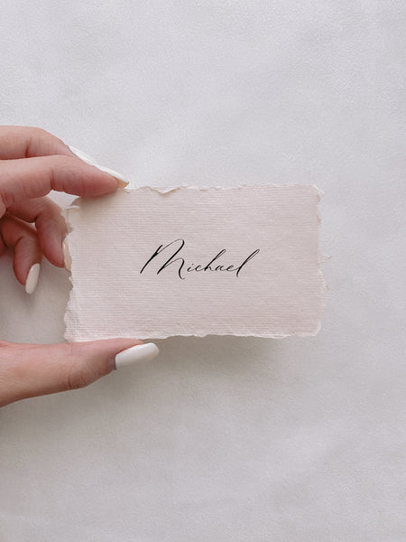handmade paper place card in light cream color hand lettered in modern calligraphy in black ink