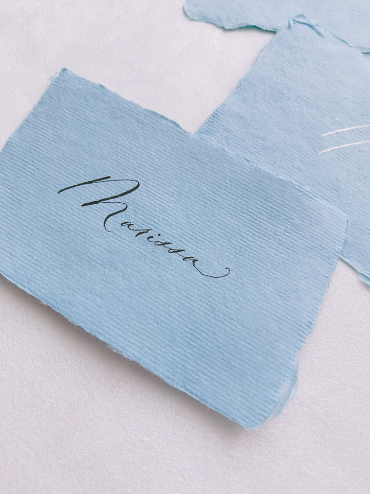 handmade paper place card in sky color hand lettered in modern calligraphy in black ink_side angle