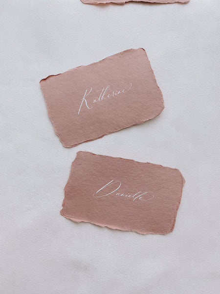 handmade paper place cards in terracotta color hand lettered in modern calligraphy in white ink_front angle