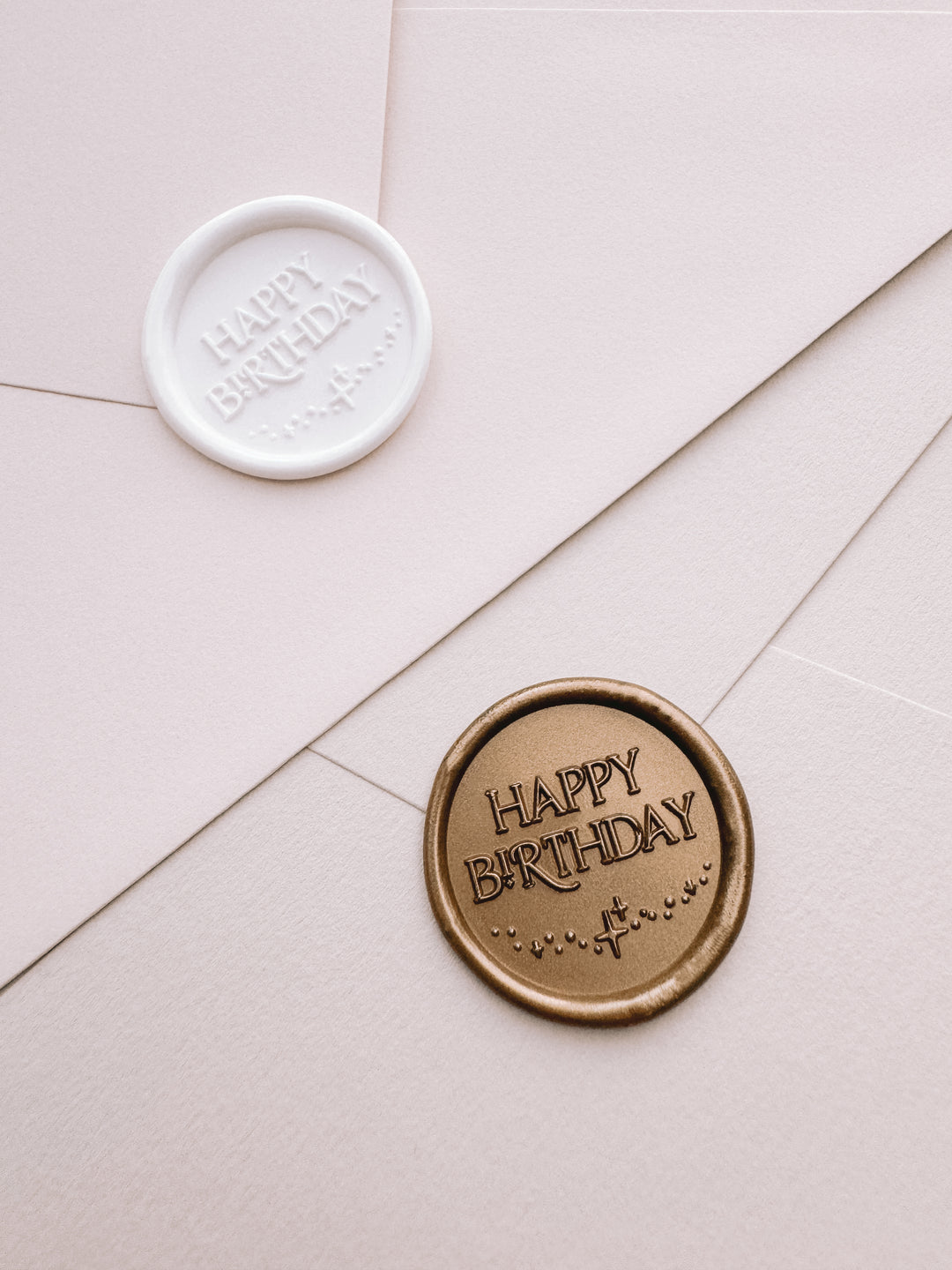 Gold and white Happy Birthday wax seals on light beige envelopes