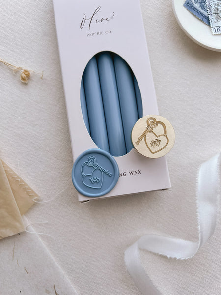 Dusty blue personalized monogram heart shaped lock with key wax seal design featuring custom initials on a box of dusty blue sealing wax sticks 