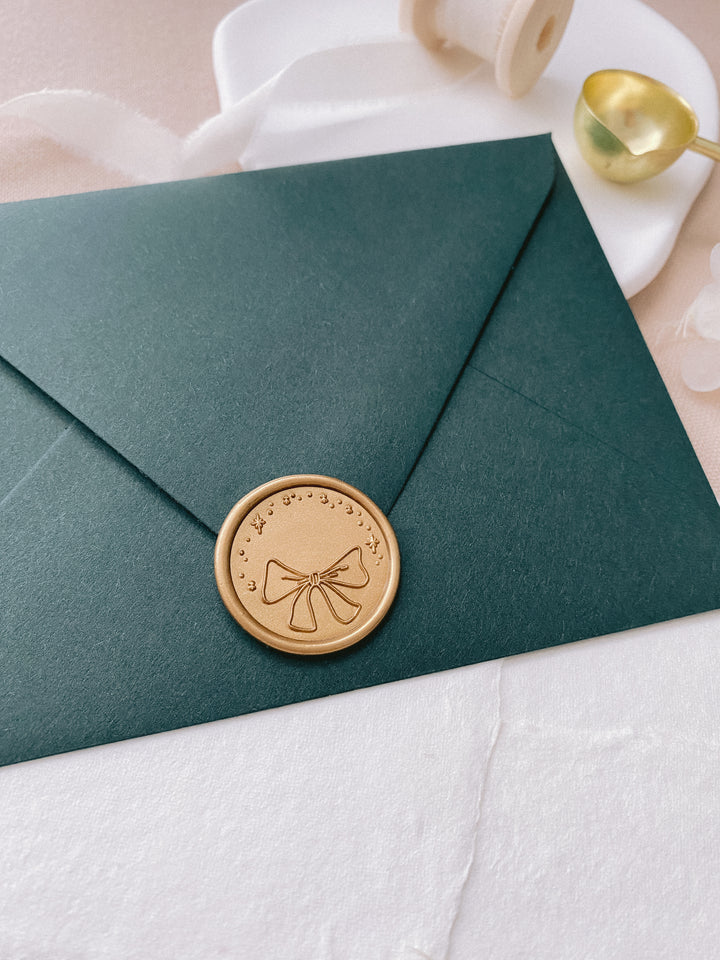 Gold holiday bow wax seal on Christmas card envelope