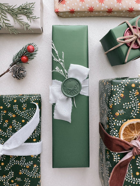 green holiday bow wax seal on Christmas gift wrapping