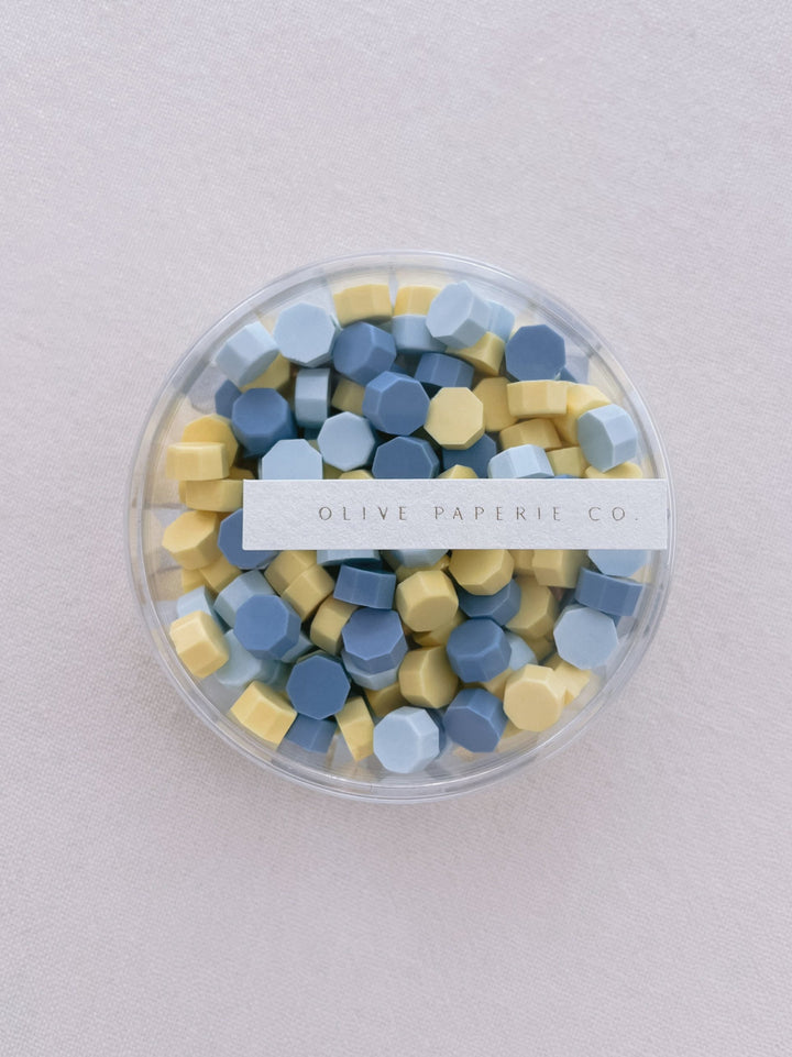 Assorted blue and yellow sealing wax beads in a clear container box