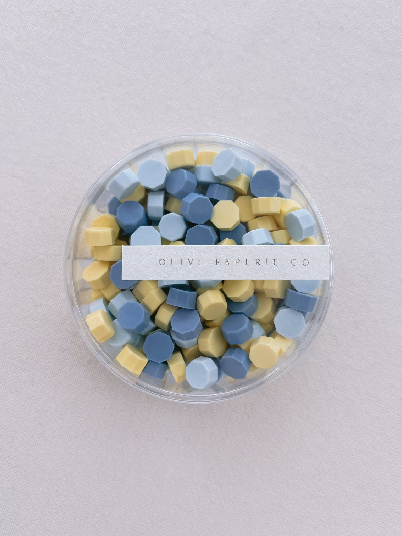Assorted blue and yellow sealing wax beads in a clear container box