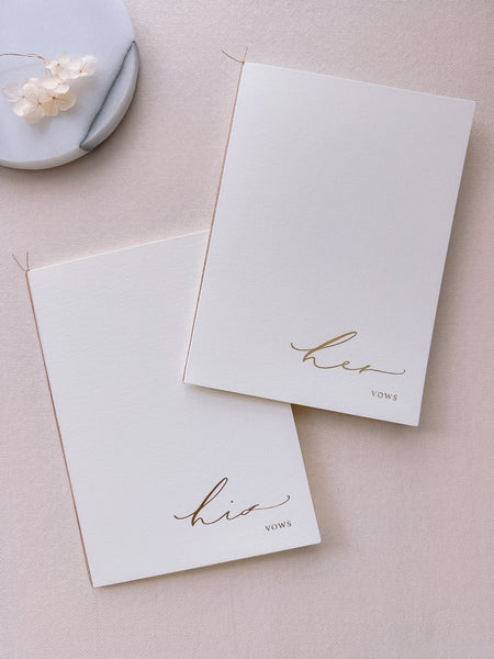 A set of two His and Her gold foil ivory card stock vow books in calligraphy script with fine brown twine
