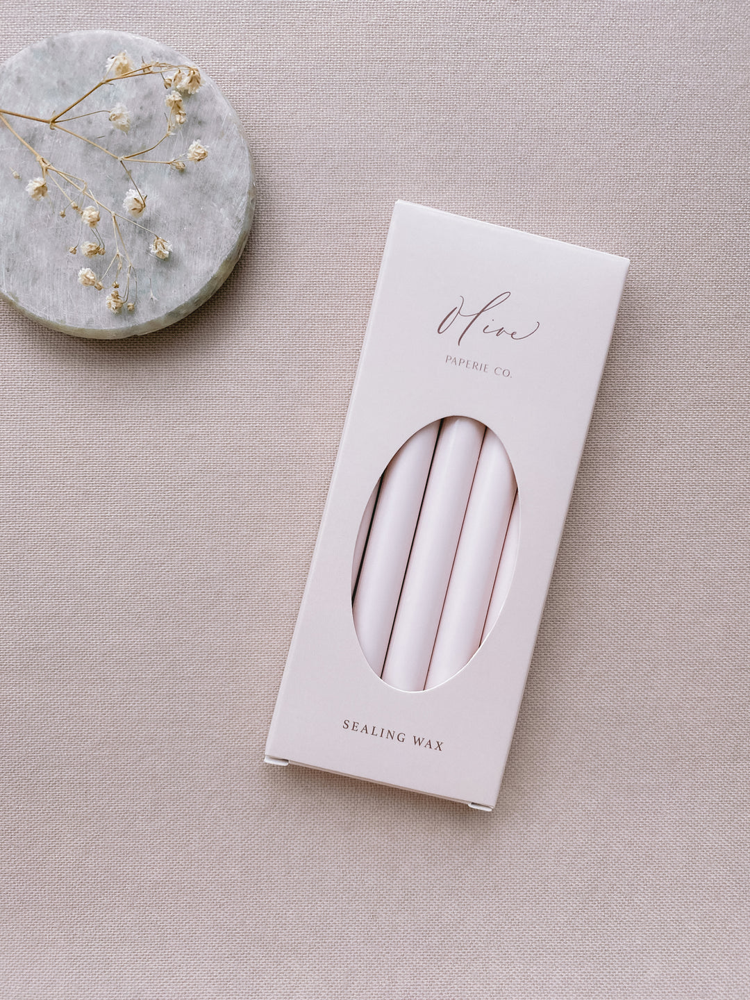 a box of 5 glue gun sealing wax sticks in ivory nude color styled with small gray stone dish and dried flowers 