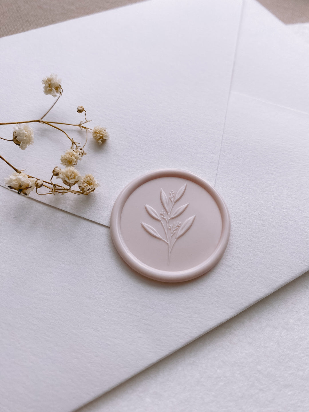 leaf branch wax seal in ivory nude color on white paper envelope styled with dried flowers