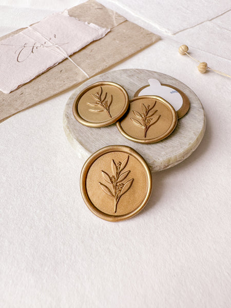 Leaf branch gold wax seals styled with a small gray stone dish, handmade paper and a dried floral branch