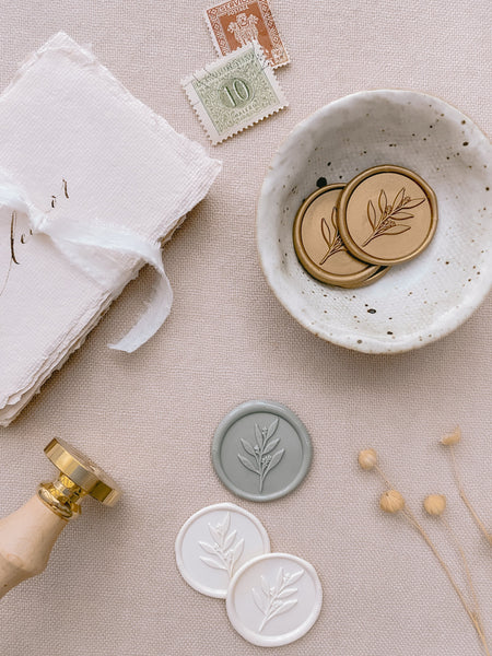 Gold, off-white and sage green leaf branch wax seals styled with wax seal stamp with wooden handle and a strand of white silk ribbon