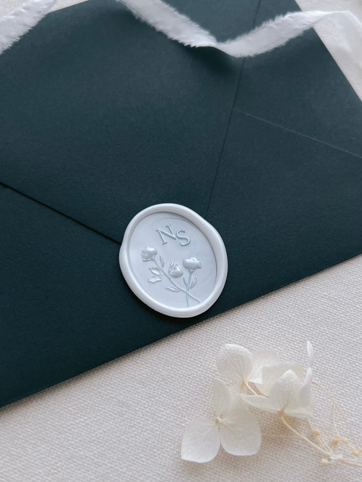 Pearl white 3D floral design custom initials wax seal on a dark blue green envelope