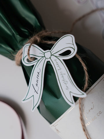 Letterpress die-cut bow gift tag on a holiday gift with 'Merry Christmas' text, tied with brown twine