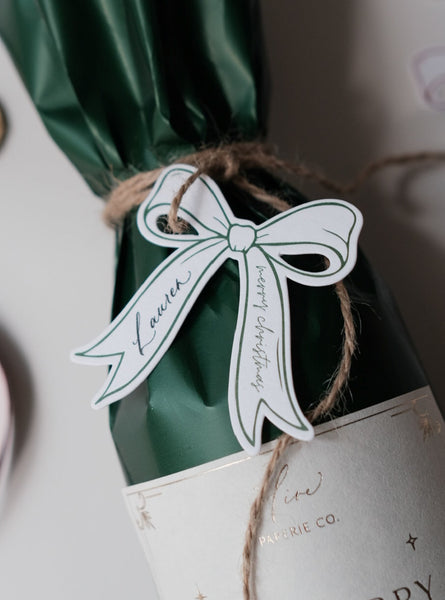 Letterpress die-cut bow gift tag on a holiday gift with 'Merry Christmas' text, tied with brown twine