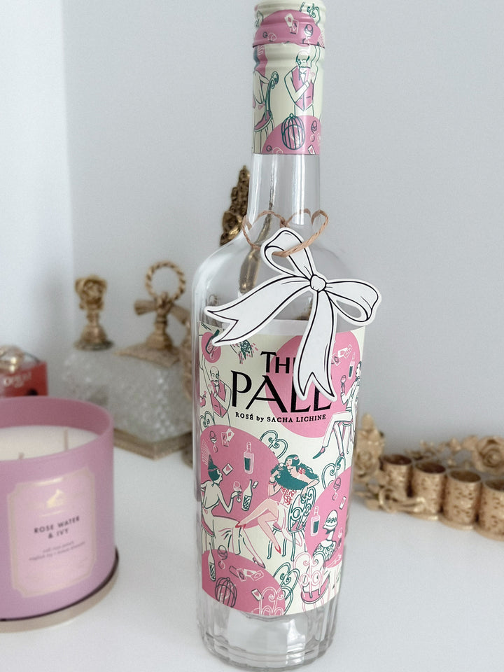 Black die-cut bow shaped gift tag hanging on a wine bottle