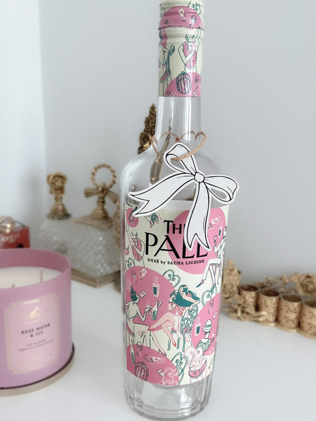 Black die-cut bow shaped gift tag hanging on a wine bottle