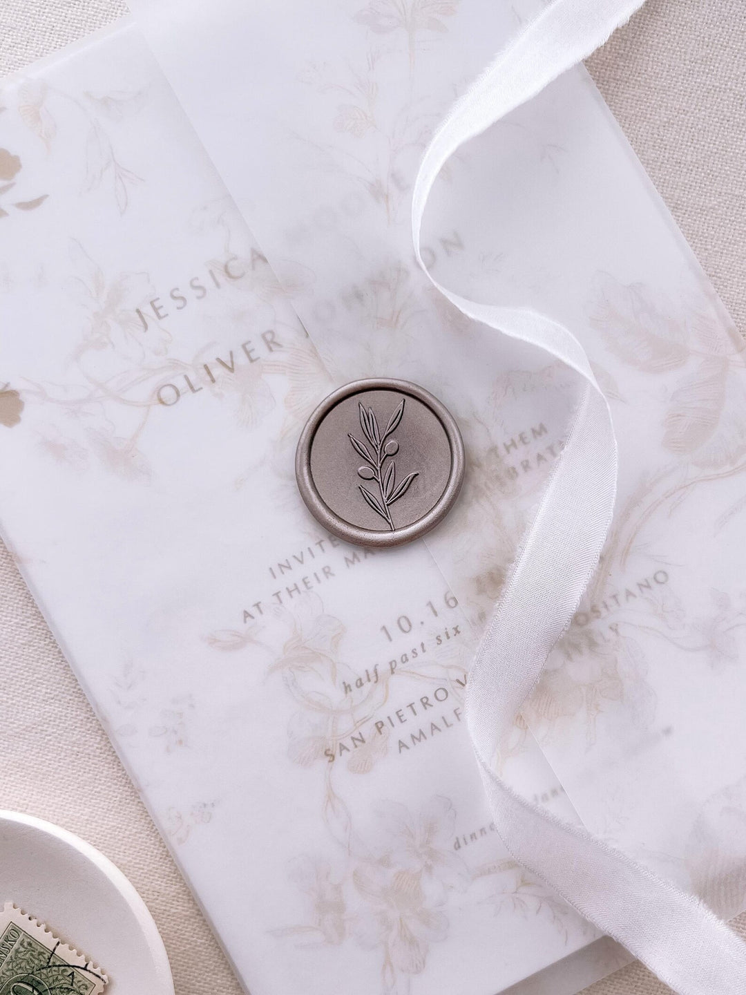 light bronze olive branch wax seal on a beige floral print vellum jacket